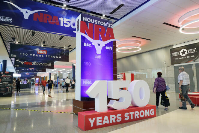 Convention attendants walk past some of the signage in the hallways outside of the exhibit halls at the NRA Annual Meeting held at the George R. Brown Convention Center Thursday, May 26, 2022, in Houston. (AP Photo/Michael Wyke)