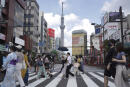 FILE - People walk along a pedestrian crossing in the tourist district of Asakusa, near the landmark Tokyo Skytree tower in Tokyo, Japan on Saturday, July 31, 2021. Japan will reopen its borders to foreign tourists June 10, 2022, but only to package tour participants for now, officials said Thursday, as the country starts to cautiously open its borders to foreign tourism for the first time in about two years. (AP Photo/Kantaro Komiya, File)