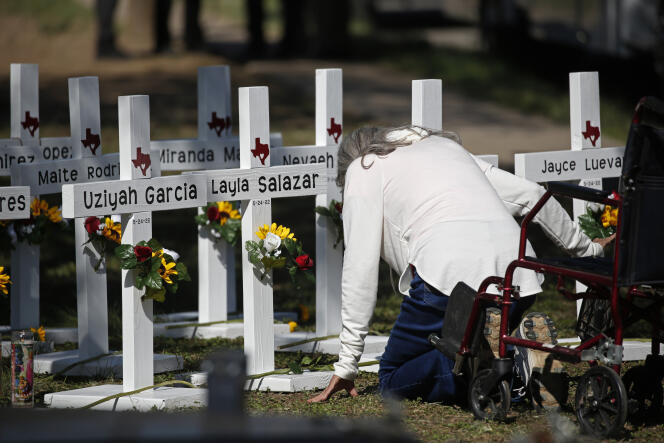 Una mujer medita frente a cruces con los nombres de los niños muertos, frente a la Escuela Primaria Robb en Uvalde (Texas), el 26 de mayo de 2022.