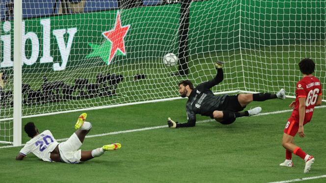 Real Madrid's Brazilian forward Vinicius Junior (L) scores the opening goal past Liverpool's Brazilian goalkeeper Alisson Becker during the UEFA Champions League final, on May 28, 2022.