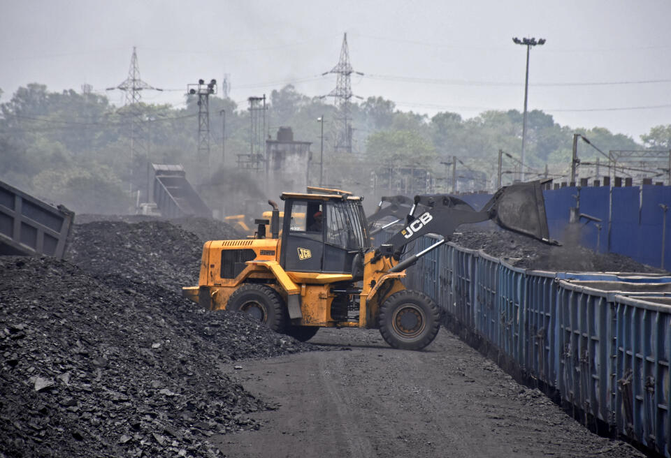 A worker operates a JCB machine to load coal onto a goods train at the Amrapali coal mines in Peeparwar in India's Jharkhand state on April 30, 2022. - Power cuts in both India and Pakistan were partly blamed on shortages of coal after an unusually hot March and April pushed up power demand and ate up stockpiles. (Photo by AFP)