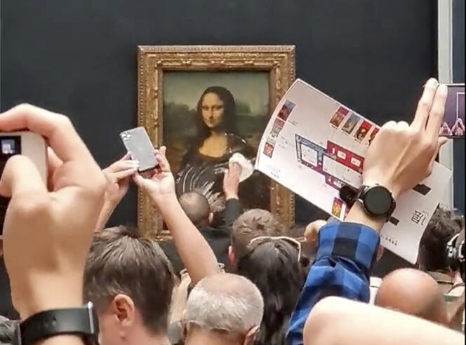 A security guard cleans the smeared cream from the glass protecting the Mona Lisa at the Louvre Museum, in Paris, France, Sunday, May 29, 2022.