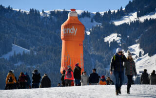 People gather near a special shaped hot air balloon promoting a hand wash product from Switzerland's largest retail company Migros on the opening day of the 39th International Hot Air Balloon festival in the Swiss Alps skiing resort of Chateau-d'Oex on January 21, 2017. - Dozens of balloons from 15 countries are participating in the 39th International Hot Air Balloon festival, taking place from January 21 to 29 in Chateau-d'Oex. (Photo by FABRICE COFFRINI / AFP)