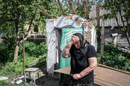 Andrievka- rue Oleksiy Mel. Région de Kyiv- Ukraine- 25 mai 2022- Madame Kravtchenya, devant l’entrée du cellier où elle se refugiait avec sa famille . Son fils Iouri a été tué quelques rue plus loin par les soldats russes. Des voisins l’auraient dénoncé, en l'accusant de dénoncé l'enemi. Le lendemain, 3 avril, 3 soldats russes sont venu chercher son deuxième fils Maxime. Elle les a supplié de ne pas le tuer. L’officier russe semble avoir été pris de pitié, il l'a épargné.