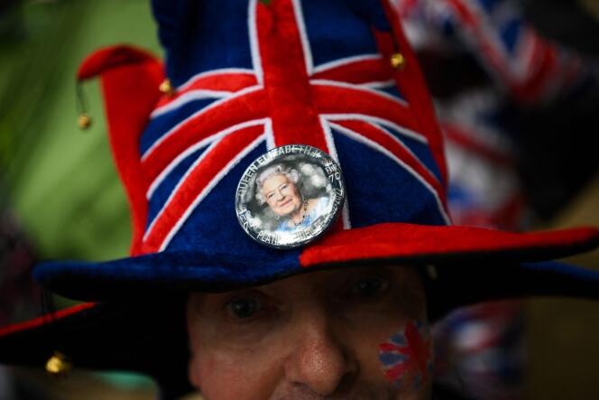 A man wears a portrait of the queen in his Union Jack hat in London on June 1, 2022.