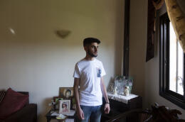 Elio Fikany stands in the living room of his family’s apartment in Rayyak, in the Bekaa Valley, east Lebanon, Friday, May 27, 2022.
