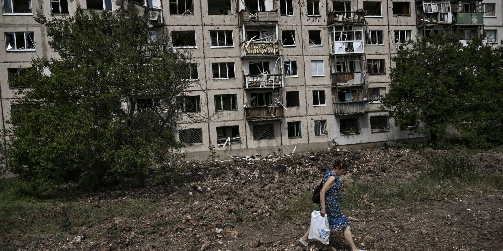 Une Ukrainienne marche devant un immeuble résidentiel endommagé par une frappe de missiles russes dans la ville de Soledar, non loin de Sievierodonestk, dans le Donbass, à l’est de l’Ukraine, le 4 juin 2022.