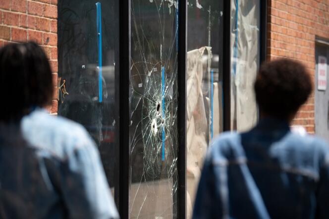 Pedestrians walk past bullet holes in the window of a store front on South Street in Philadelphia, Pennsylvania, the day after a mass shooting left three dead and multiple people injured. Three people were killed and 11 others wounded late on June 4, 2022, in the US city of Philadelphia after multiple shooters opened fire into a crowd on a busy street, police said. (Photo by Kriston Jae Bethel / AFP)