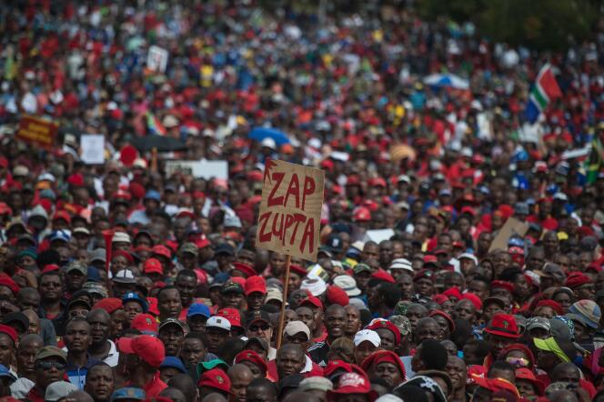 Lors d’une manifestation pour demander la démission du président  sud-africain Jacob Zuma, le 12 avril 2017, à Pretoria. Un homme tient une pancarte sur laquelle on peut lire « Zap Zupta » en référence à M. Zuma et à ses liens avec la famille Gupta. Une fratrie accusée d’avoir pillé les caisses de l’Etat avec la complicité de l’ex-président.