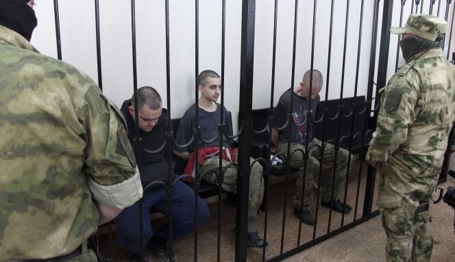 Two British citizens Aiden Aslin, left, and Shaun Pinner, right, and Moroccan Saaudun Brahim, center, sit behind bars in a courtroom in Donetsk, in the territory which is under the Government of the Donetsk People's Republic control, eastern Ukraine, Thursday, June 9, 2022. 