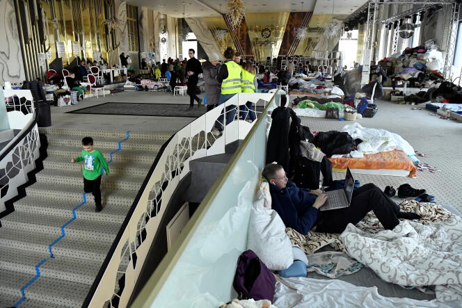 Des réfugiés ukrainiens se reposent dans une salle de bal convertie en abri temporaire, dans l’hôtel Mandachi, au poste frontière de Suceava, Roumanie, le 20 mars 2022. 