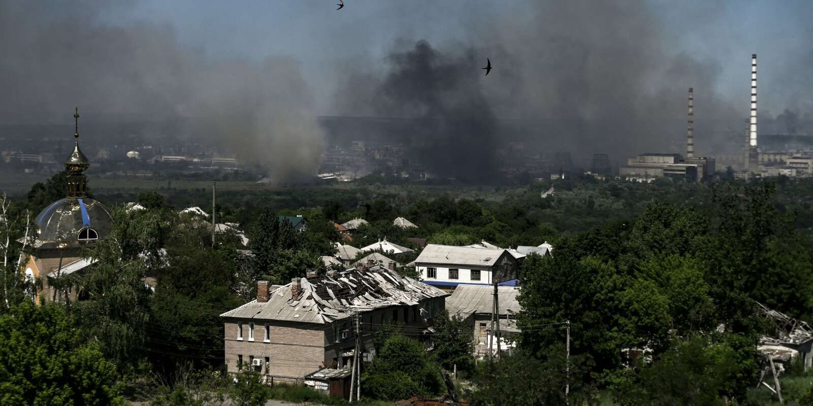 Un bâtiment endommagé à Lyssytchansk alors que de la fumée noire s’élèvent de la ville voisine de Sievierodonetsk dans la région de Donbass, dans l’est de l’Ukraine, le 9 juin 2022.