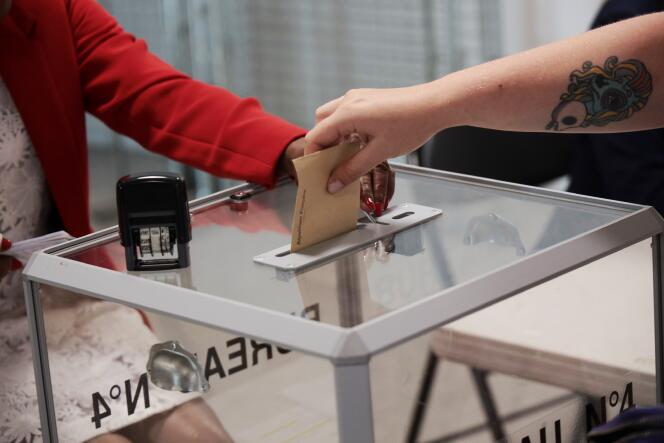 Une femme s'apprête à déposer son bulletin de vote dans l'urne du bureau de vote numéro 4 à Hénin-Beaumont, le 12 juin 2022.