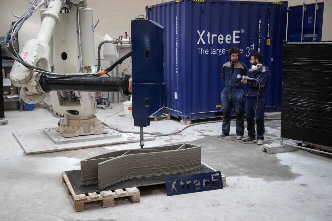 Des employés de la start-up XtreeE observent un bras robotisé imprimant un mur en béton, à Rungis (Val-de-Marne), en 2019.