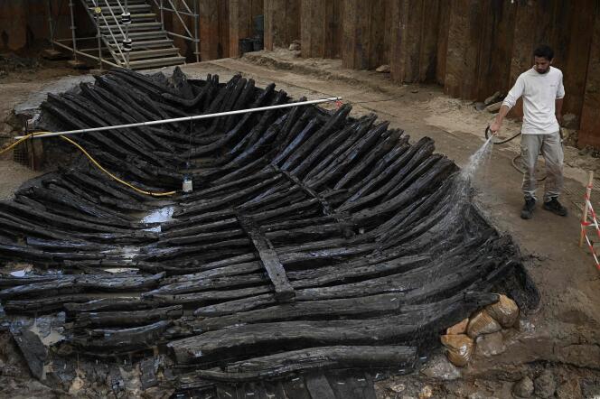 To protect it, an archaeologist from Inrap wets the 1,300-year-old wreck unearthed in Villenave-d'Ornon, near Bordeaux, during its presentation to the press on June 14, 2022.