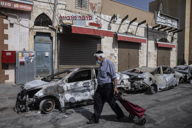 Un homme passe devant des voitures incendiées après une nuit de violence entre des manifestants arabes israéliens et la police dans la ville de Lod, au centre d’Israël, mardi 11 mai 2021.