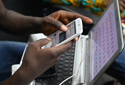 A student of the Virtual University of Ivory Coast (UVCI) takes a class on his mobile phone on November 28, 2019 in Abidjan - The first promotion of the Virtual University of Ivory Coast (UVCI), or 830 students, graduated on November 28, receiving a degree in the digital sciences, issued by this institution created in 2015 to unclog the university system. (Photo by ISSOUF SANOGO / AFP)