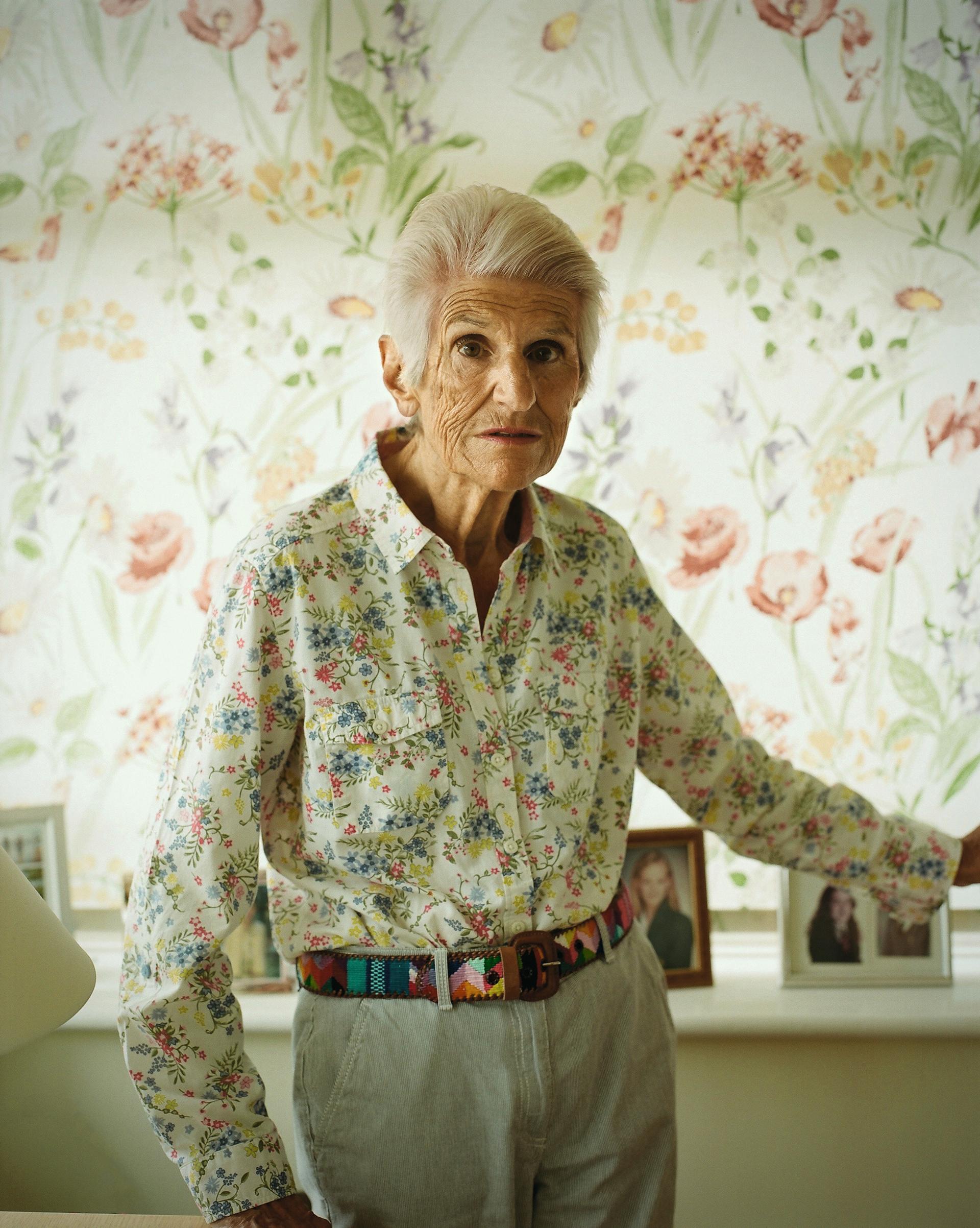 Veronica Smith le 26 mai chez elle, près de Brighton. Derrière elle, les photos des enfants et petits-enfants de son mari, et une de son petit-enfant à elle, né de sa fille, avec laquelle elle a repris contact.