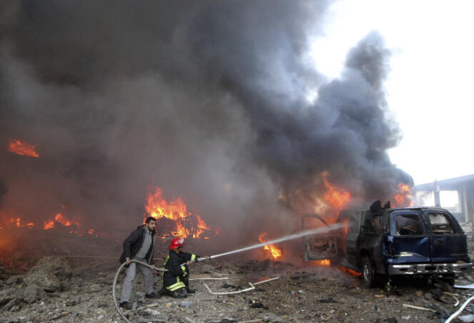 Rescue personnel hose down a burning vehicle after a bomb blast that targeted the covoy of Prime Minister Rafik Hariri in Beirut Monday, February 14, 2005.