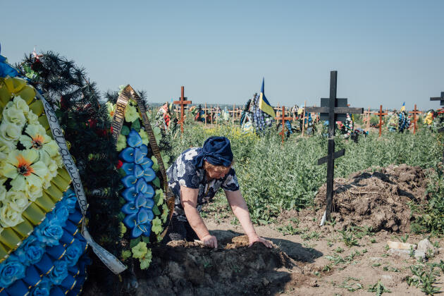 A woman tends to the grave of a soldier at the Krasnopilske cemetery in Dnipro on June 12, 2022.