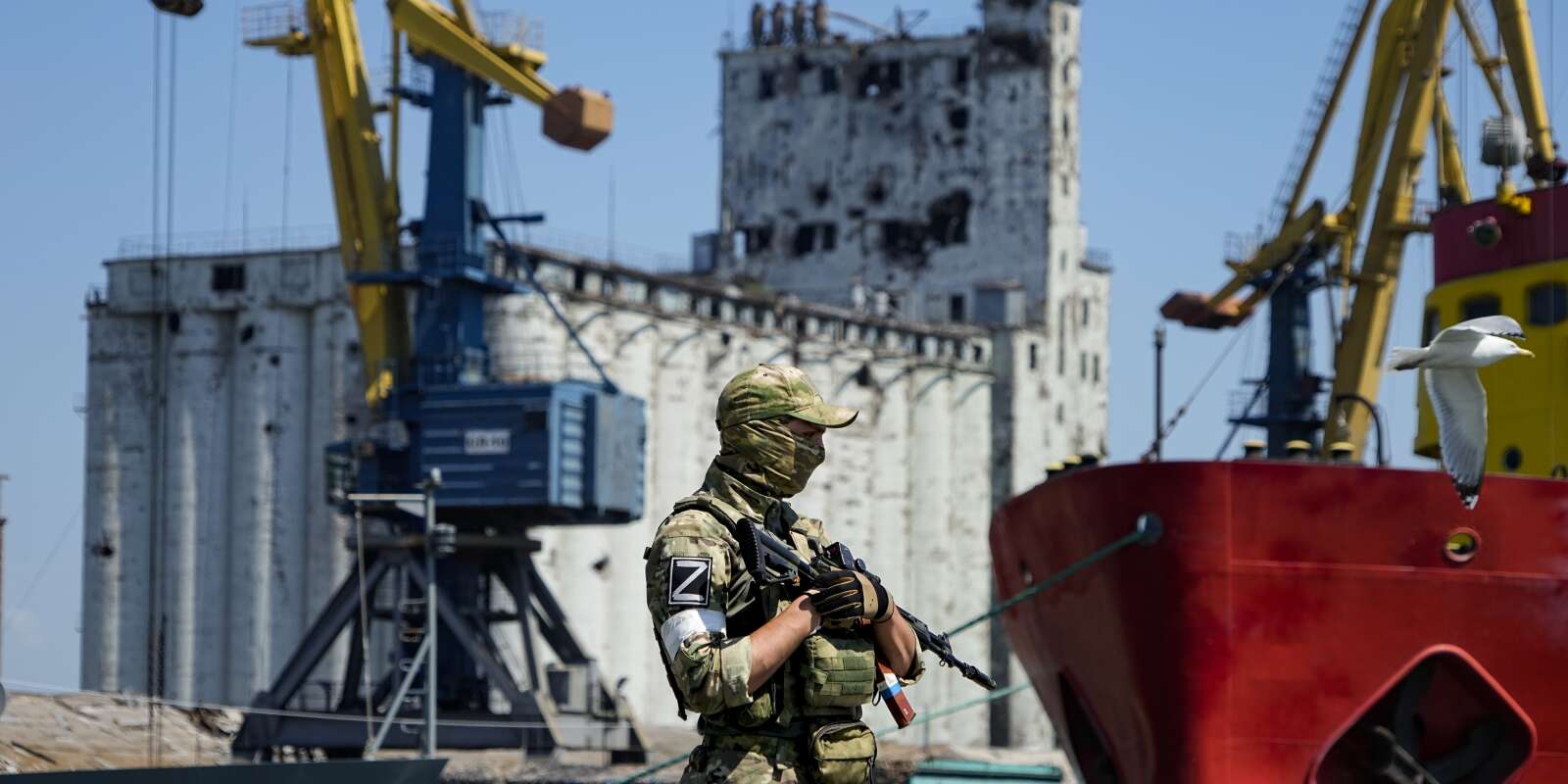 Soldat russe devant un silo à grain endommagé, sur les quais du port de Marioupol, en Ukraine, le 12 juin 2022.