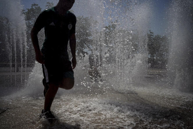 A man runs in a fountain in Lyon, France, on June 19, 2022, during a heat wave. 