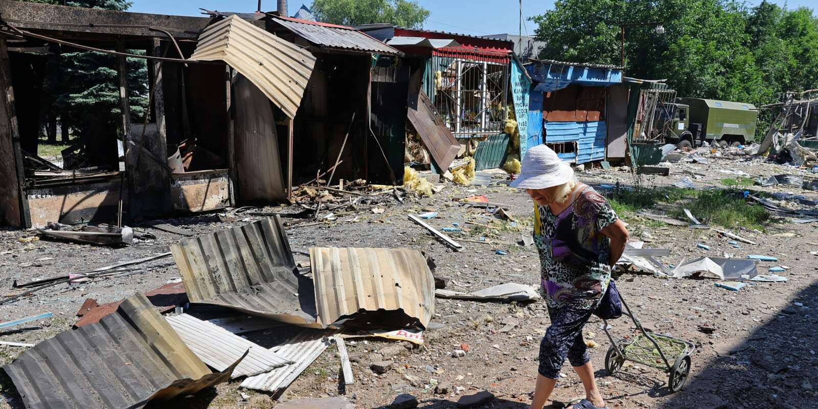 Une femme passe devant des structures détruites sur un marché local de Donetsk, le 19 juin 2022, après de récents bombardements.