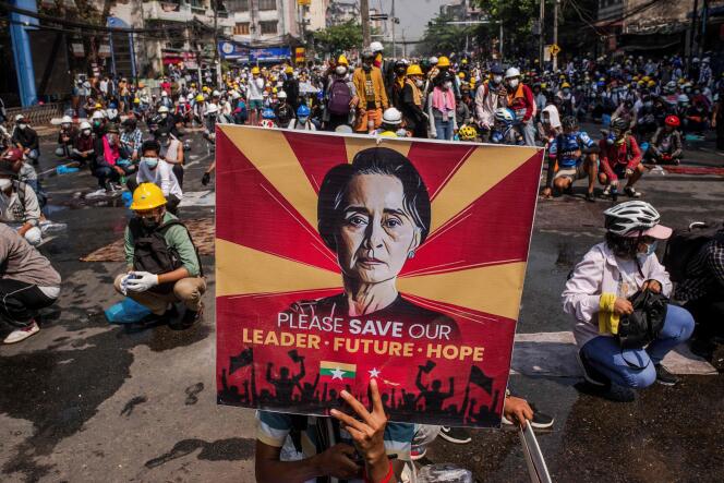 In this file photo taken on March 2, 2021, a protester holds a poster featuring detained civilian leader Aung San Suu Kyi during a demonstration against the military coup in Yangon. 