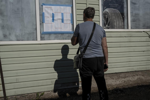 Près de Zaporijia, en Ukraine, un homme regarde, le 16 juin 2022, la liste indiquant les 172 voitures qui devaient pouvoir partir en convoi ce jour-là, vers des zones occupées par les Russes. 