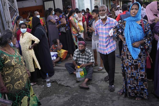 People wait near an empty fuel station hoping to buy kerosene oil for cooking in Colombo, Sri Lanka, Thursday, May 26, 2022.