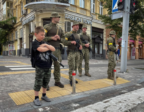 Un enfant avec un jouet fusil se met à coté d'une unité de patrouille ukrainienne au centre de Kiev, Ukraine le 22 Juin 2022.