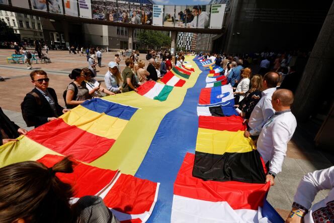 Devant le Parlement européen, des dpéutés européens et des représentants ukrainiens déroule un drapeau de 30 mètres de long mêlant le drapeau ukrainien aux drapeaux des membres de l’Union européenne, le 23 juin 2022.