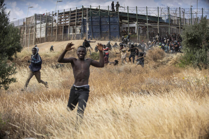 Migrants run on Spanish soil after crossing the fence separating the Spanish enclave of Melilla from Morocco. Spain, Friday, June 24, 2022.
