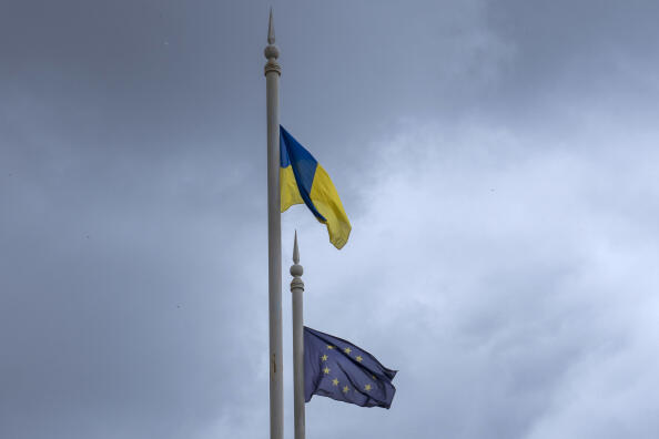 The Ukrainian flag, left, and EU flag fly on poles, in Kyiv, Ukraine, Thursday, June 23, 2022. European Union leaders on Thursday are set to grant Ukraine candidate status to join the 27-nation bloc, a first step in a long and unpredictable journey toward full membership that could take many years to achieve. (AP Photo/Nariman El-Mofty)
