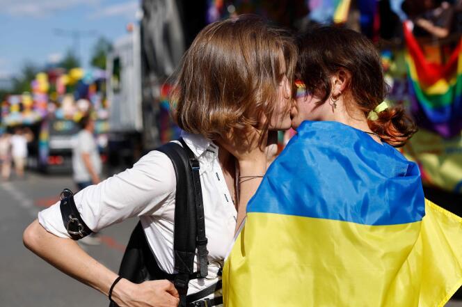 Two women, one wrapped in a Ukrainian flag, embrace during the Pride march in Warsaw, June 25, 2022. 