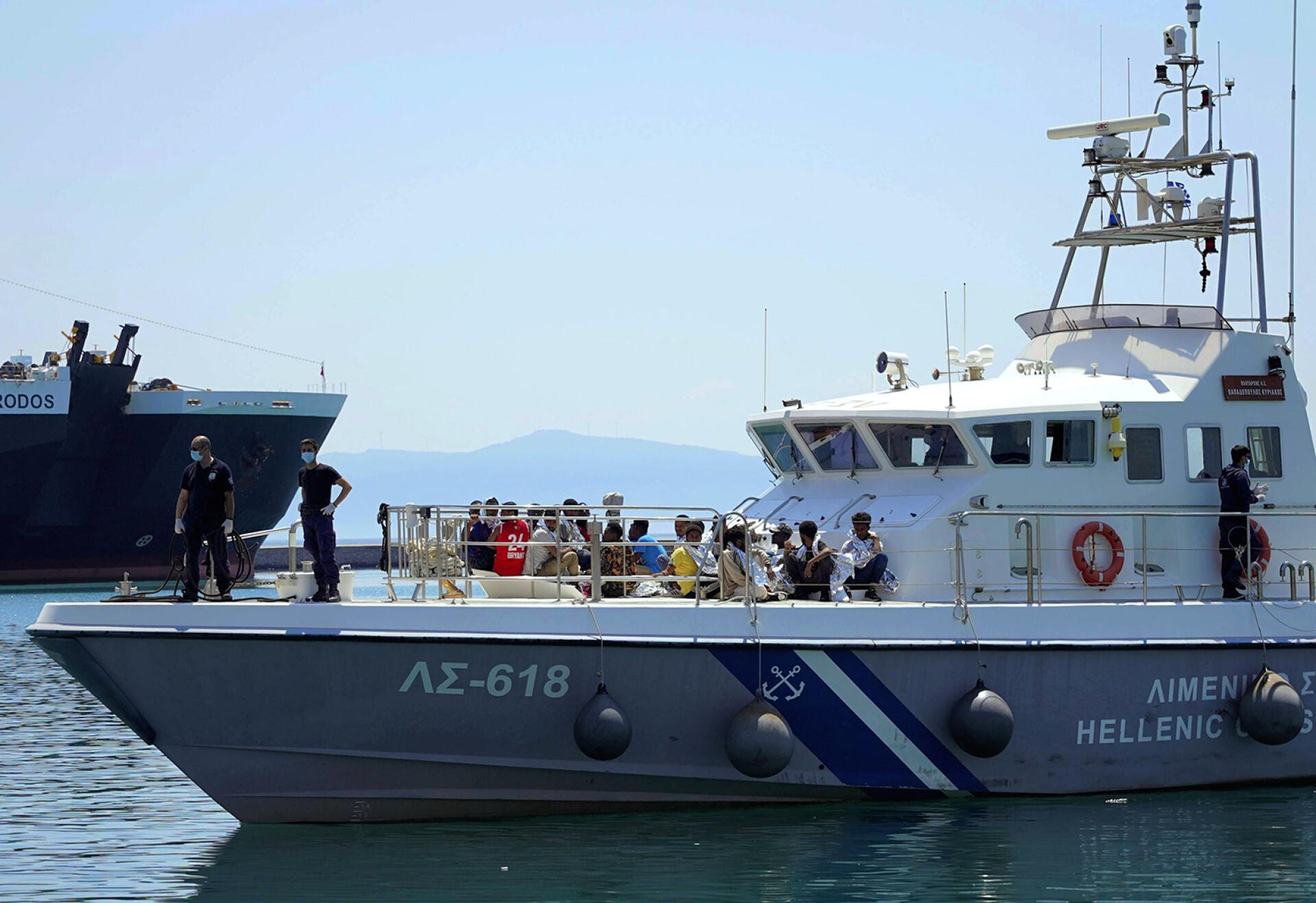 Des migrants assis sur le pont d’un bateau des gardes-côtes grecs, dans le port de Mytilène, sur l’île de Lesbos, le 22 juin 2022.