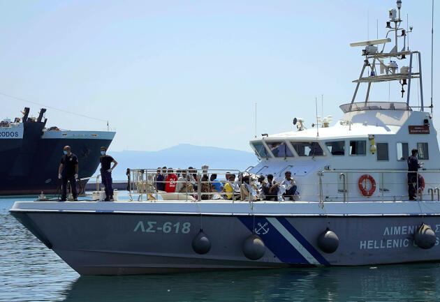 Des migrants assis sur le pont d’un bateau des garde-côtes grec, dans le port de Mytilène, sur l’île de Lesbos, le 22 juin 2022.