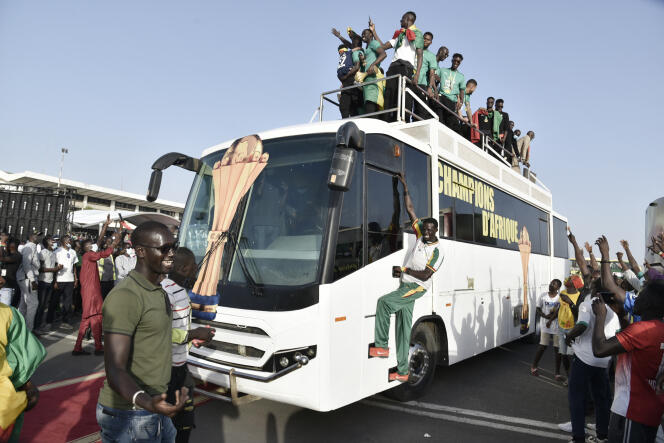 Des supporteurs entourent le bus transportant l’équipe sénégalaise de football à Dakar, le 7 février 2022, sur le tarmac de l’aéroport Léopold-Sédar-Senghor où ils ont atterri du Cameroun après avoir remporté la Coupe d’Afrique des nations.
