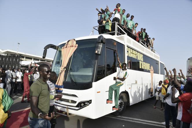 Los seguidores rodean el autobús que lleva al equipo de fútbol de Senegal a Dakar, el 7 de febrero de 2022, en la pista del aeropuerto Léopold-Sédar-Senghor, donde aterrizaron desde Camerún después de ganar la Copa Africana de Naciones.