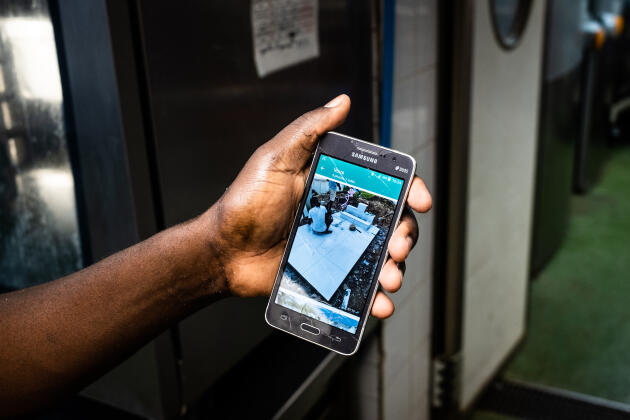 Dieuvenor, a dishwasher at the Café du Commerce, shows a photo of his mother's funeral that took place the week before in Haiti. Unable to attend, he asked a trusted friend to represent him. Paris, June 2022.