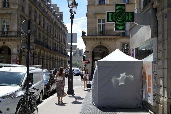 Des piétons passent devant une tente de dépistage, à Paris, le 29 juin 2022. 