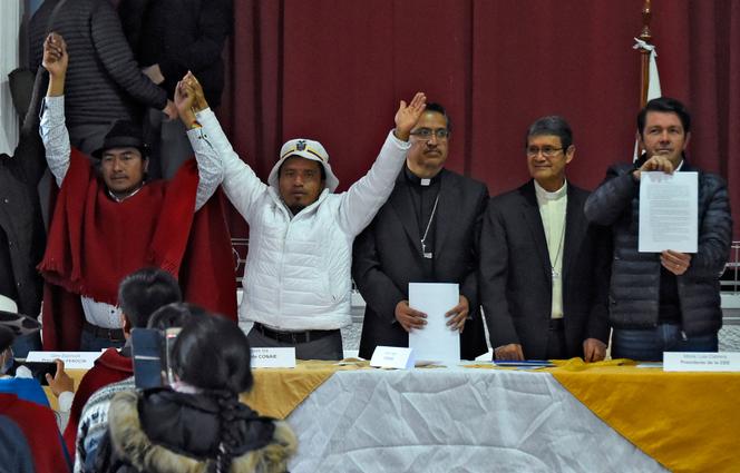 Ecuador's Minister of Government Francisco Jimenez (right) shows a document as the president of the Confederation of Indigenous Nationalities in Ecuador (Conaie), Leonidas Iza (left) raises his arms with the presence of the Secretary General of the Episcopal Conference of Ecuador (CEE), Monsignor David de la Torre (center) and the President of the CEE, Luis Cabrera, (2nd to the right) after indigenous leaders and the government reach an agreement to end to cost-of-living protests that have largely paralyzed the country since June 13, at the CEE headquarters in Quito on June 30, 2022. 