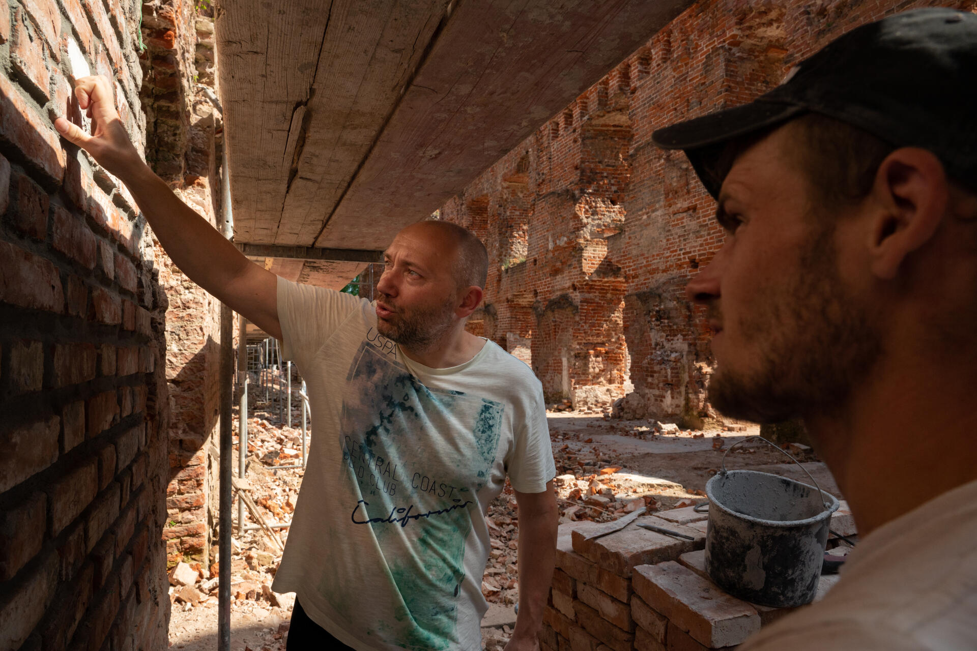 Ivan Artioukh, a contractor, talks with workers about progress on the Ragnit Castle's restoration in Neman on June 27, 2022.