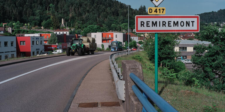 The sign of entry of the city with in the distance the traffic circle where are the shops. On a traffic circle at the entrance of Remiremont, two models of bakeries oppose each other. Remiremont, France, June 18, 2022, for Le Monde.