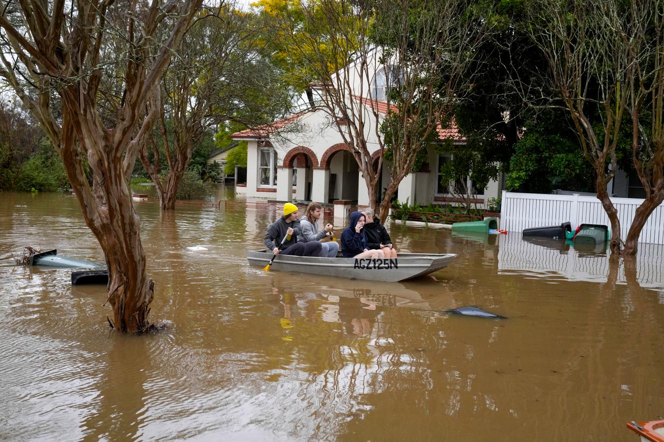 People paddle through a flooded street in Windsor, a suburb of Sydney, Australia, on Tuesday, July 5, 2022. Hundreds of homes have been flooded in and around Australia's largest city.