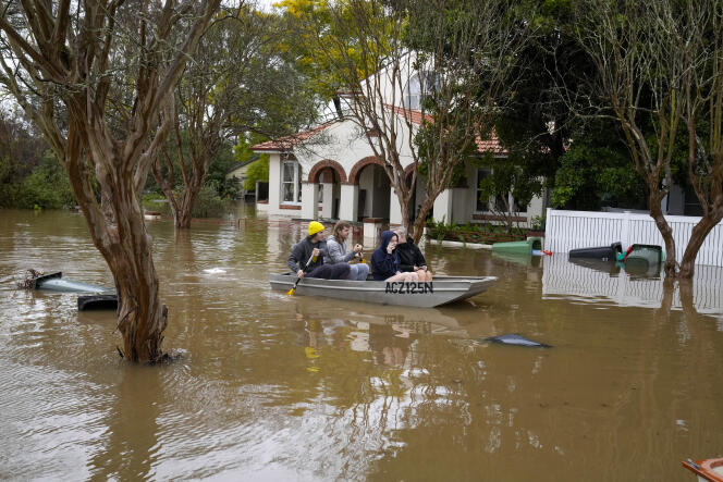 People paddle through a flooded street at Windsor on the outskirts of Sydney, Australia, Tuesday, July 5, 2022. 