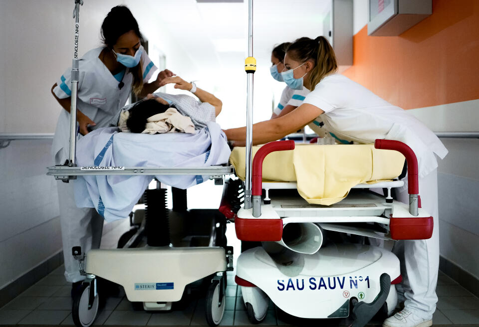 Trois infirmières transposent une patiente sur un nouveau brancard aux Urgences de l’Hopital de la Source à Orléans le 15 juin 2022.