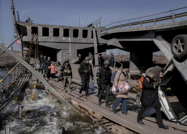 Des civils ukrainiens aux côtés de soldats évacuent les zones de combats en passant par le pont d’Irpine, en Ukraine, le 11 mars 2022.