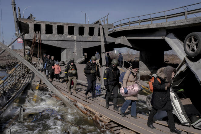 Ukrainian civilians alongside soldiers evacuate from combat zones across Irpin Bridge in Ukraine on March 11, 2022.