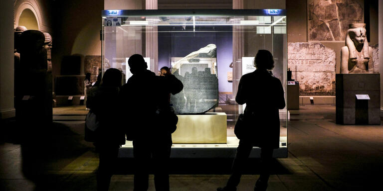 Visitors view the Rosetta Stone, the Ancient Egyptian stone stele dating to the reign of King Ptolemy V Epiphanes (204-180 BC), at the British Museum in London on November 13, 2018. - The Rosetta Stone was instrumental in the decoding of Egyptian hieroglyphics by 19th century French scholar Jean-François Champollion as it bears matching inscriptions in hieroglyphic, demotic Egyptian, and Greek scripts, and which was discovered in Egypt's northern town of Rosetta in July 1799 by French officer Pierre-François Bouchard during Napoleon Bonaparte's campaign in Egypt.The Napoleonic campaign in Egypt and Palestine, which marked the start of modern European colonialism in the Middle East, remains contentious two centuries after the French emperor's death. The Corsican general set sail eastwards with 300 ships in 1798, aiming to conquer Egypt and block a crucial route between Britain and its colonies in India (Photo by Amir MAKAR / AFP)